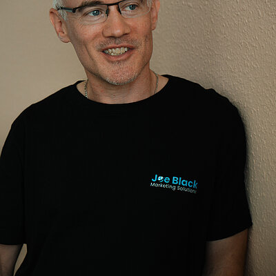 Joe Black in seinem Büro mit schwarzem Firmenshirt