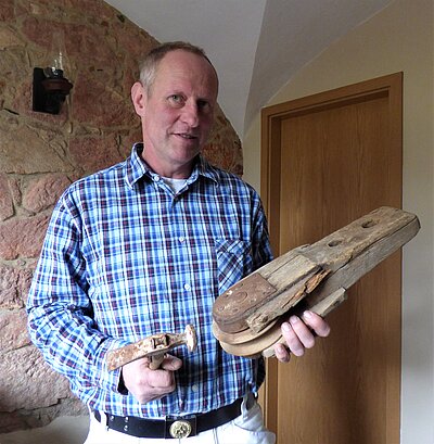 Mario Hammer mit alten Holzwerkzeugen in der Hand.