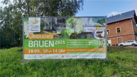 Ein großes Mashbanner vor dem ehemaligen Halsbrücker Bahnhof macht auf die Nestbau-Veranstaltung „Ländliches Bauen“ am 18. September aufmerksam.