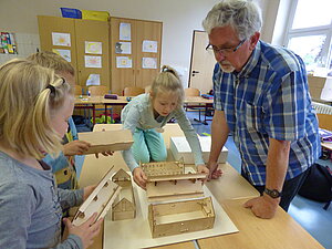 Foto zeigt Veranstaltungsreihe "Kleine Baumeister" der Nestbau-Zentrale Mittelsachsen. Projekttag an einer Grundschule. Architekt Herr Dittrich zeigt Schülern den Aufbau eines Fachwerkhauses.