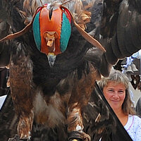 Jagd mmit Greifvogel: Foto zeigt einen Mann mit einem großen Greifvogel, der eine Kappe auf dem Kopf hat