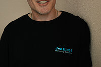 Joe Black in seinem Büro mit schwarzem Firmenshirt