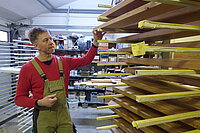 Geschäftsführer Jan Göhler steht an einem Stapel zu bearbeitender Holzbretter