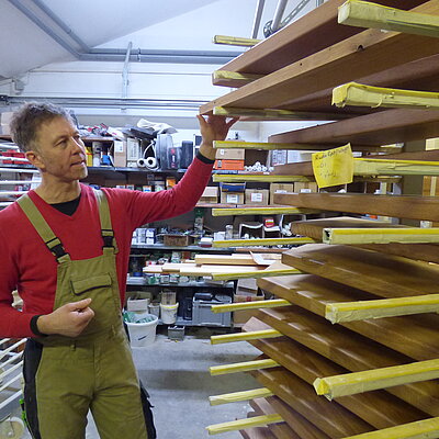 Geschäftsführer Jan Göhler steht an einem Stapel zu bearbeitender Holzbretter
