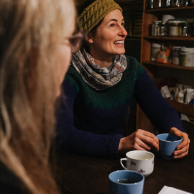 Kristin Häuser sitzt mit Nestbau-Koordinatorin am Tisch und erzählt von ihrem Weg in die Region, während sie eine Tasse Tee trinken.