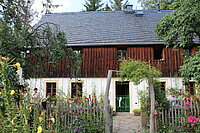 Foto zeigt das Wohnhaus des Hofes mit üppigem Bauerngarten