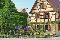 Foto zeigt die Vorderseite des Fachwerkhauses in Klosterbuch mit grünem Vorgarten und Wäsche auf der Leine